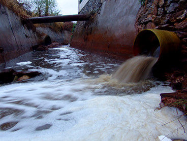 銅陵市循環經濟工業園通過一根直徑超過50厘米的塑料管道將污水打進園區外的一道明渠中，灰黑色的污水流速極快，水量很大。