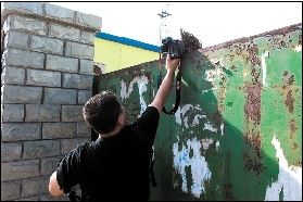 記者對廠內(nèi)情況進行拍攝時，大門后伸出一把掃帚擋鏡。