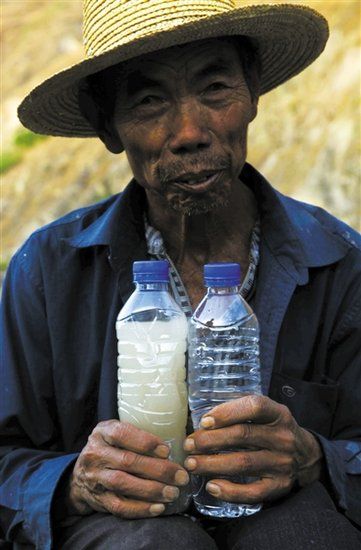 3月21日，一位村民拿著兩瓶水，里面是小江水和普通礦泉水的對比。